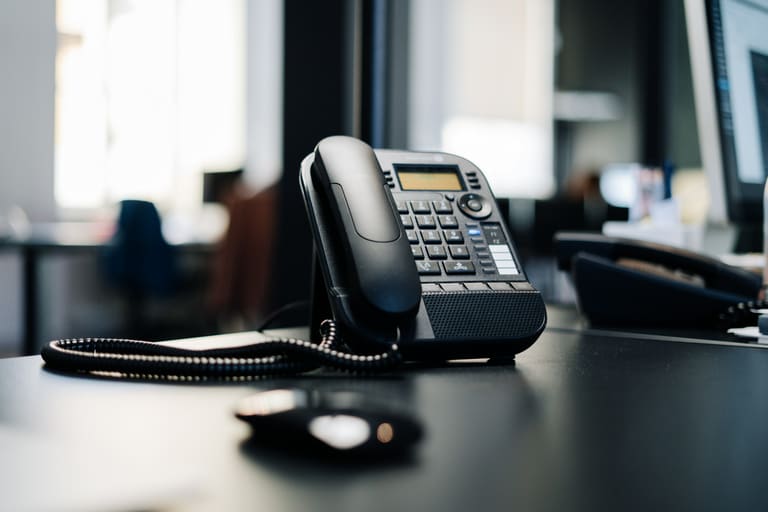 A desk phone with a keypad on an office desk